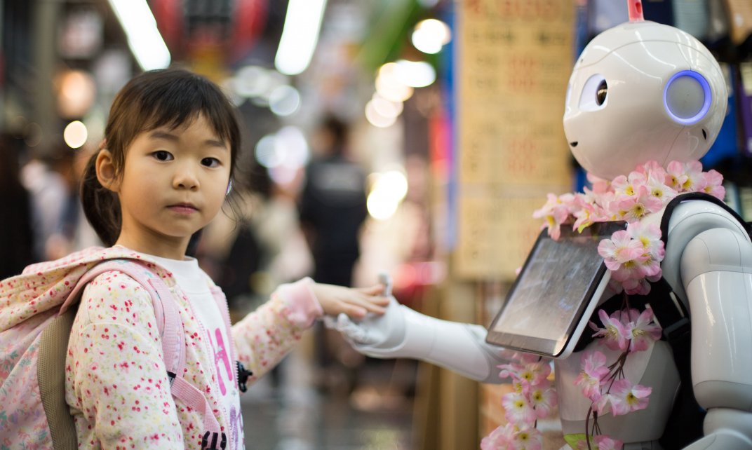 Een meisje houdt de hand vast van een robot. (Foto: Andy Kelly)