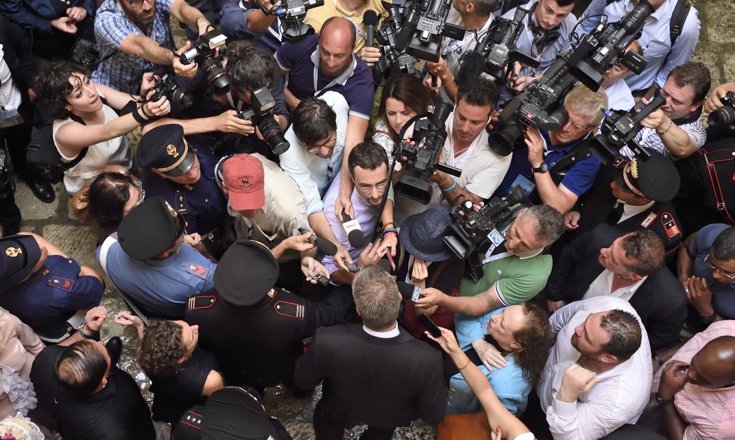 Een man staat de verzamelde pers te woord.